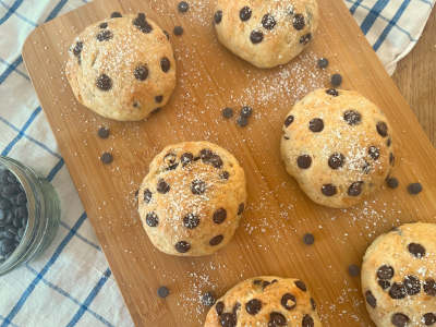 Freshly baked chocolate buns sprinkled with icing sugar on a wooden board